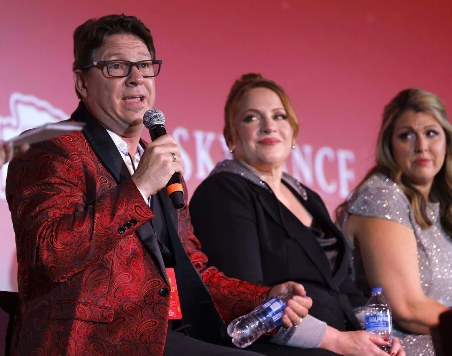KANSAS CITY, MISSOURI - NOVEMBER 30: (L-R) Dustin Rikert, Julie Sherman Wolfe, and Samantha DiPippo speak onstage during Hallmark's Premiere Screening of Holiday Touchdown: A Chiefs Love Story on November 30, 2024 in Kansas City, Missouri. (Photo by David Eulitt/Getty Images for Hallmark Media)