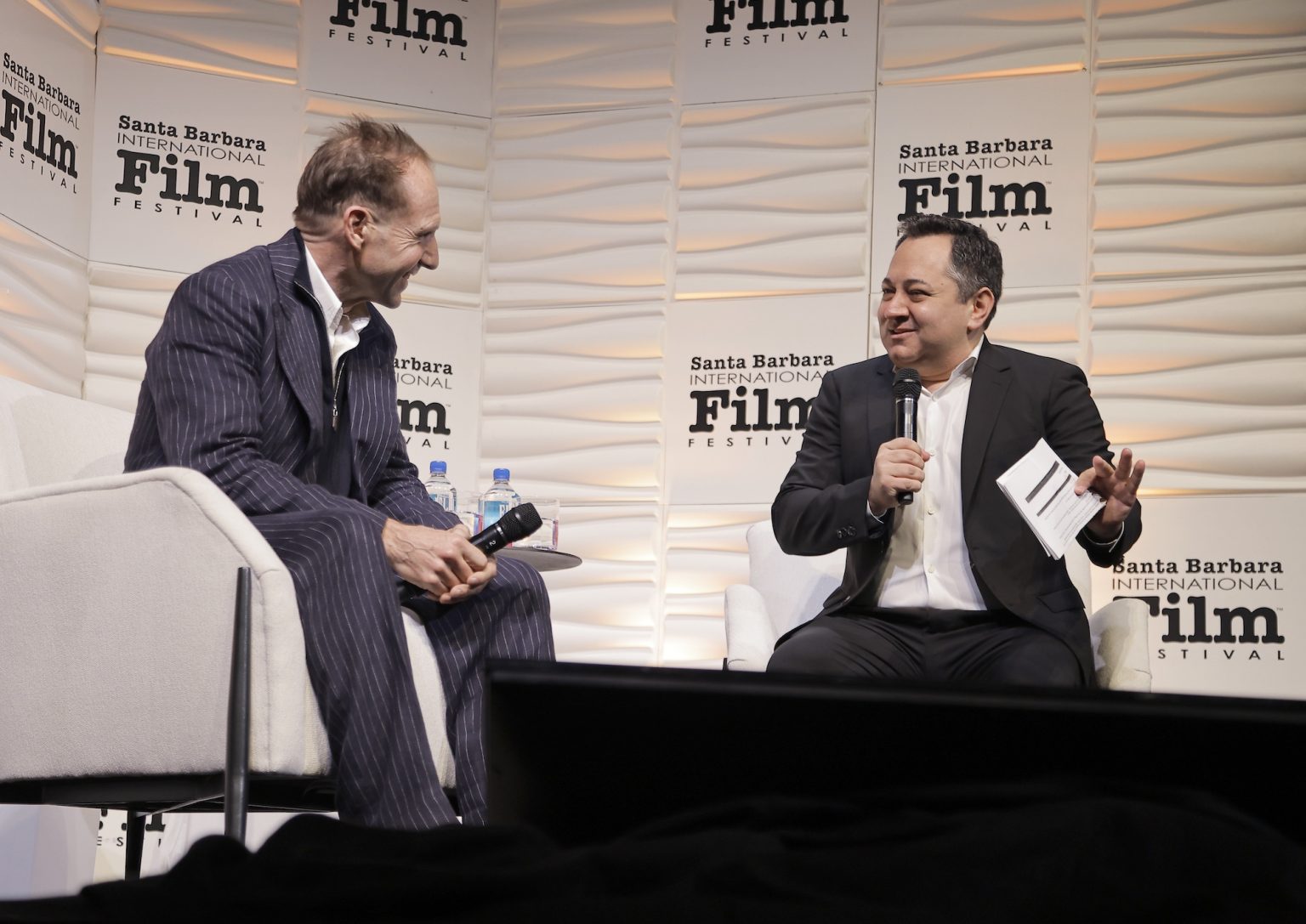 SANTA BARBARA, CALIFORNIA - FEBRUARY 06: Honoree Ralph Fiennes and Scott Feinberg speak onstage at the Outstanding Performer of the Year Award ceremony during the 40th Santa Barbara International Film Festival at Arlington Theatre on February 06, 2025 in Santa Barbara, California. (Photo by Tibrina Hobson/Getty Images for Santa Barbara International Film Festival)