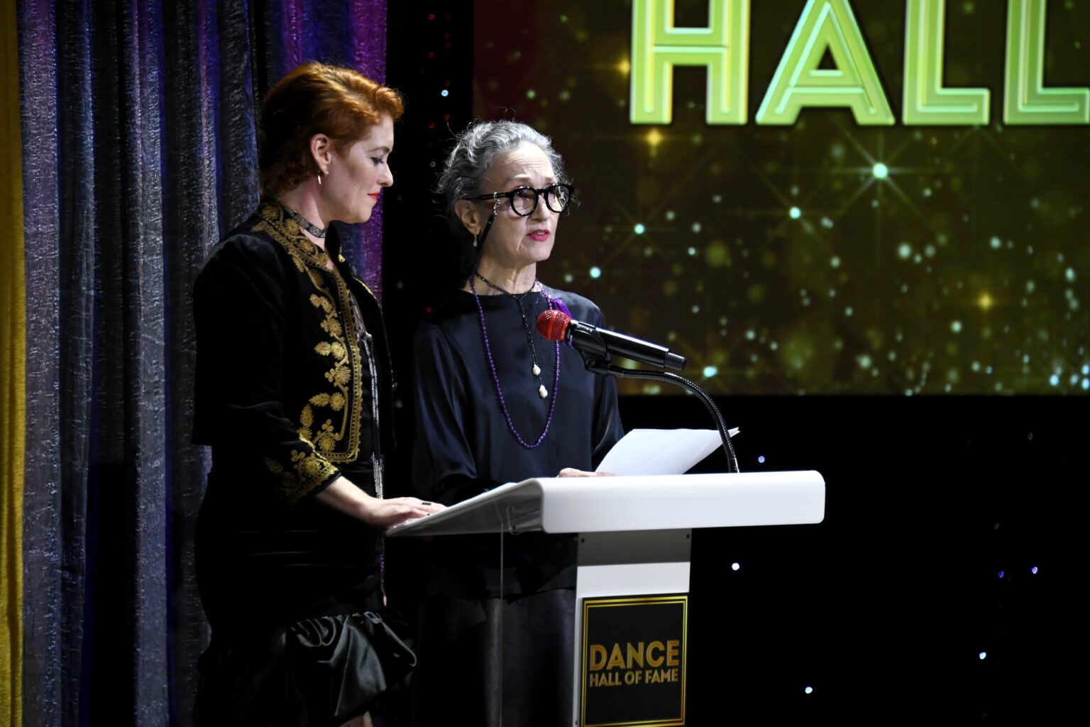 CULVER CITY, CALIFORNIA - DECEMBER 03: (L-R) Dylis Croman and Bebe Neuwirth speak onstage during the inaugural Dance Hall of Fame ceremony honoring the most influential artists in dance history at Glorya Kaufman Community Center on December 03, 2025 in Culver City, California. (Photo by Alberto E. Rodriguez/Getty Images for Dance Hall of Fame)