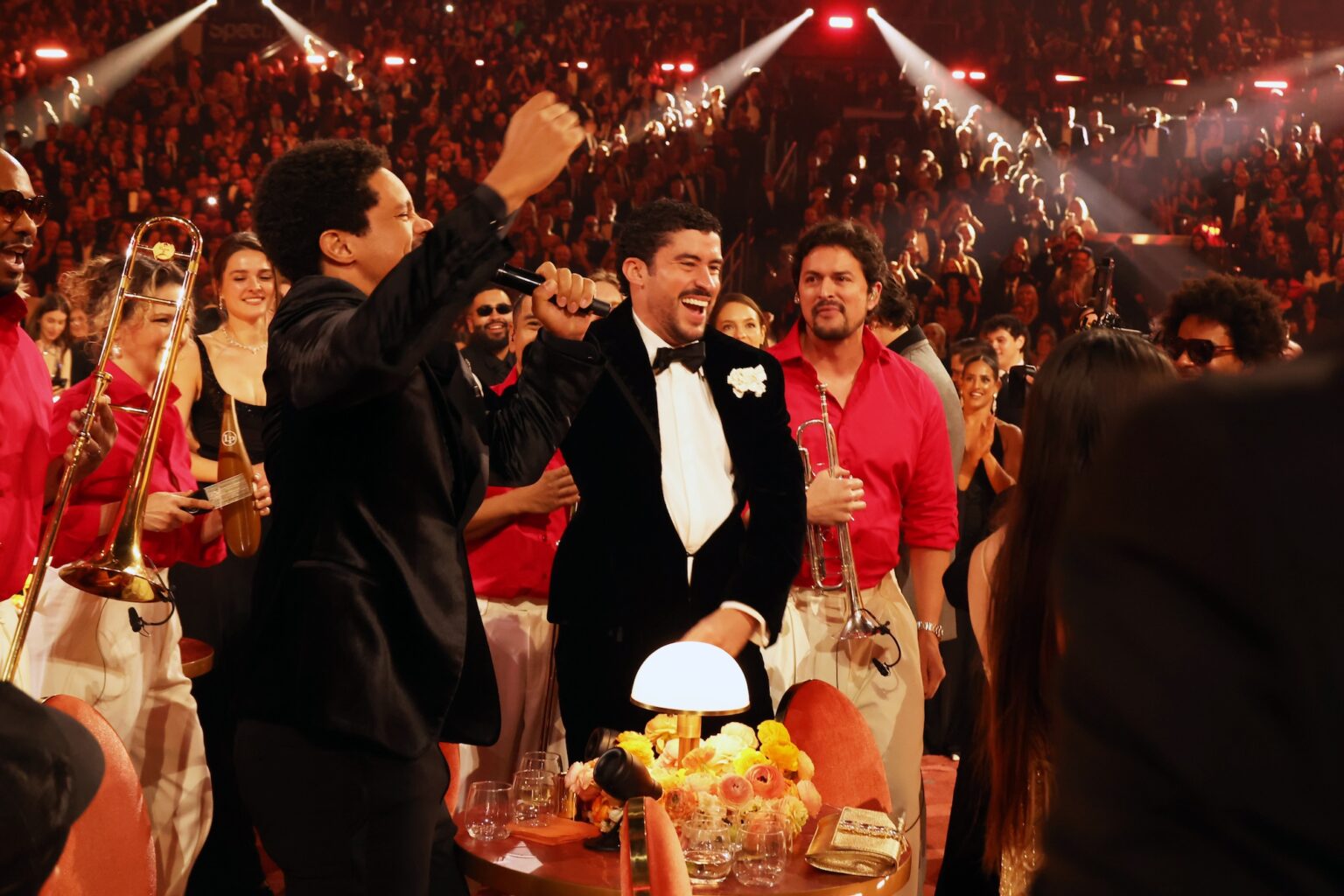 LOS ANGELES, CALIFORNIA - FEBRUARY 01: Trevor Noah and Bad Bunny sing in the audience during the 68th GRAMMY Awards at Crypto.com Arena on February 01, 2026 in Los Angeles, California. (Photo by Johnny Nunez/Getty Images for The Recording Academy)