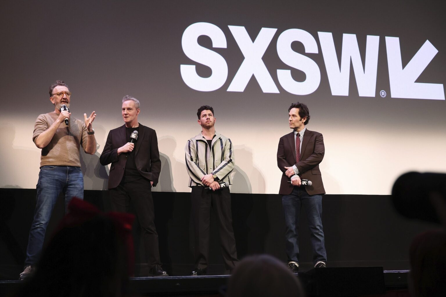 AUSTIN, TEXAS - MARCH 14: (L-R) John Carney, Peter McDonald, Nick Jonas and Paul Rudd speak onstage during the premiere of "Power Ballad" during SXSW at The Paramount Theatre on March 14, 2026 in Austin, Texas. (Photo by Robin Marchant/Getty Images for Lionsgate)