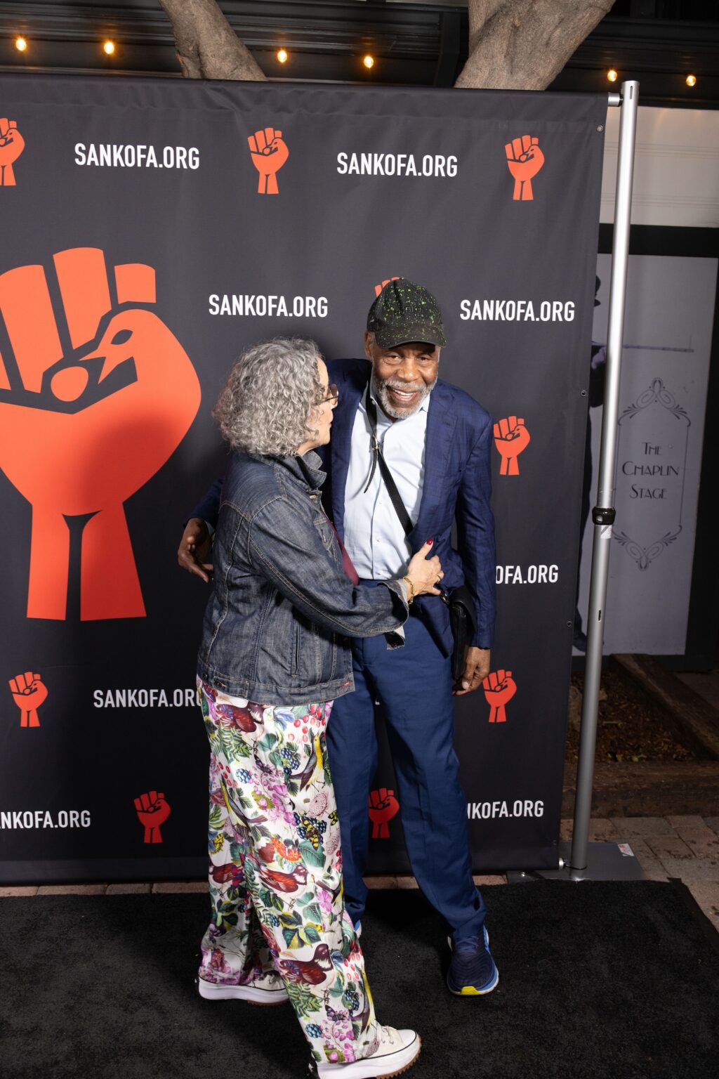 LOS ANGELES, CALIFORNIA - MARCH 1: Gina Belafonte and Danny Glover embrace at the inaugural Sankofa.org Social Justice Awards at Chaplin Studios on March 1, 2026 in Los Angeles, California. (Photo by Todd Westphal / Sankofa.org)