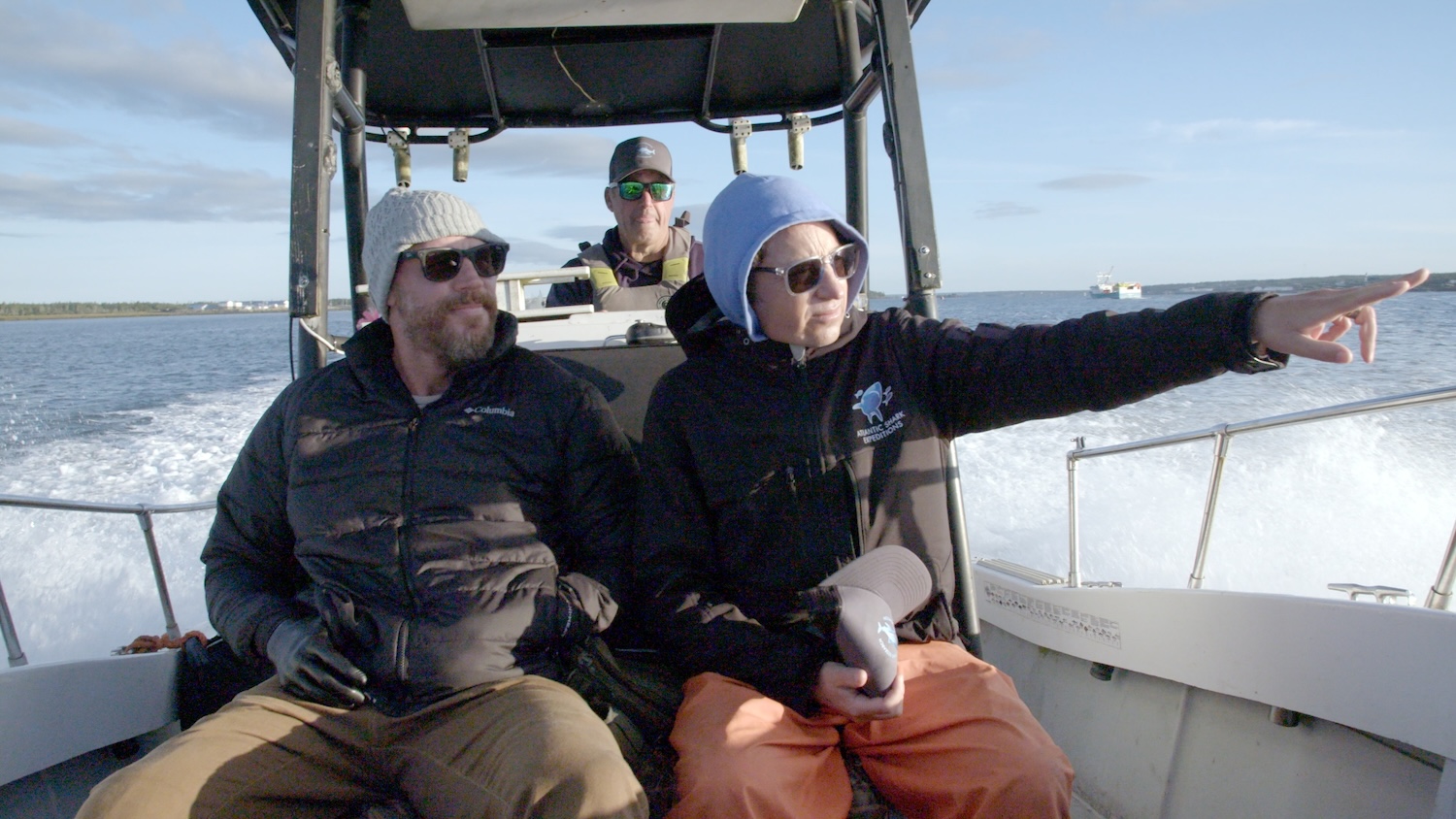 Dr. Neil Hammerschlag riding on the back of the boat with Paul de Gelder, points to something in the distance